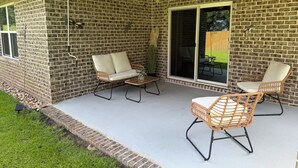 Ein überdachter Patio-Bereich mit Backsteinmauern, zwei Korbstühlen, einem Tisch und Deckenventilatoren.