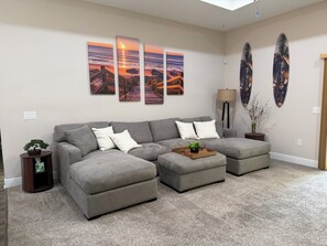 A living room with a sectional sofa, a coffee table with a plant, and wall art depicting a sunset. - Dual Master Suites~3min Walk to Water ~Sleeps 12 (Gulf Breeze)