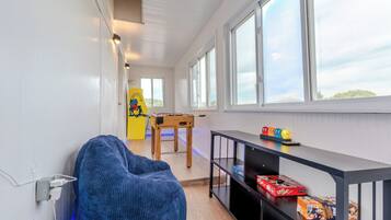 A room with a foosball table, a bean bag chair, and a table with toys and games.