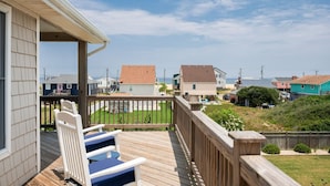 A wooden deck with a railing, a view of neighboring houses, and a clear sky. - Kitty Hawk Vacation Home with Pool, Sleeps 10 (Kitty Hawk)