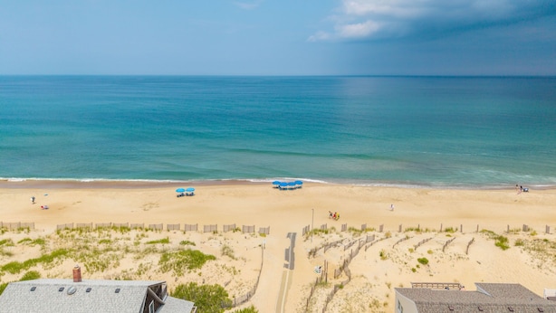 A beach view with a sandy shore, a wooden fence, and a clear sky. - Kitty Hawk Vacation Home with Pool, Sleeps 10 (Kitty Hawk)