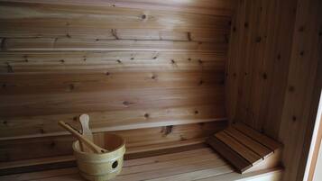 Una sauna de fusta amb una barra i un cubet de fusta amb una cullerada.