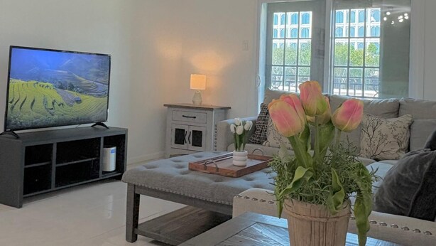 Ett vardagsrum med en tv, en soffa, ett soffbord, ett sidobord och ett fönster med utsikt.