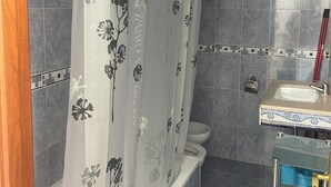 Ein Badezimmer mit Duschvorhang, Toilette und Waschbecken.