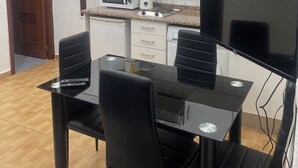 Eine kompakte Küche mit weißen Schränken, einer Mikrowelle, einer Kaffeemaschine und einem Fernseher.