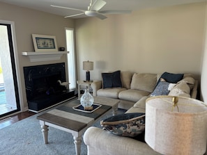 A living room with a fireplace, sofa, coffee table, and a ceiling fan.