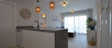 A modern kitchen with a central island, pendant lights, and a dining area with a view.