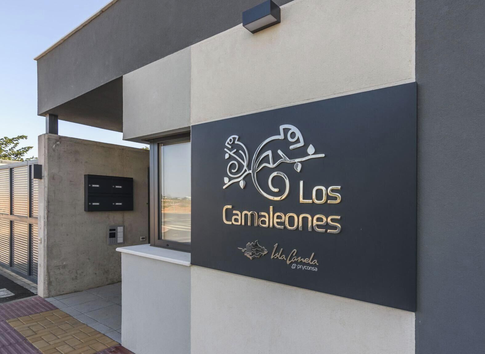A building with a sign that reads 'Los Camaleones' and 'Isla Camela Pryconsa.'