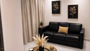 Ein modernes Wohnzimmer mit einer schwarzen Ledersofa, einem runden Couchtisch mit Dekoration und zwei gerahmten Wandbildern.