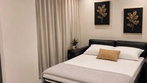 Ein modernes Schlafzimmer mit einem Bett, Vorhängen und zwei gerahmten Wandbildern.