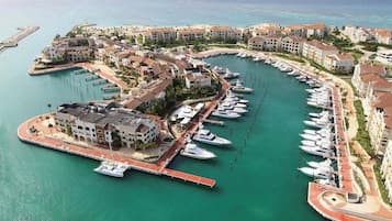 Un port de plaisance où sont amarrés des bateaux, relié à un quartier résidentiel par des bâtiments.