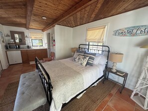 Un dormitorio con cama, mesita de noche y vistas a la cocina.