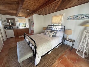 A bedroom with a bed, bedside tables, a bench, and a 'Welcome to our Coastal Cottage' sign. - Beach Bougie Retreats - Unit B (Indian Rocks Beach)