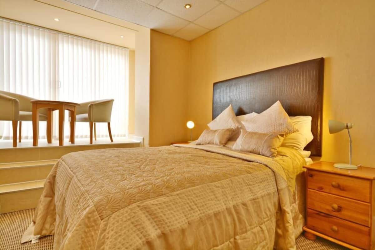 A hotel room with a bed, a desk, and a chair by the window.