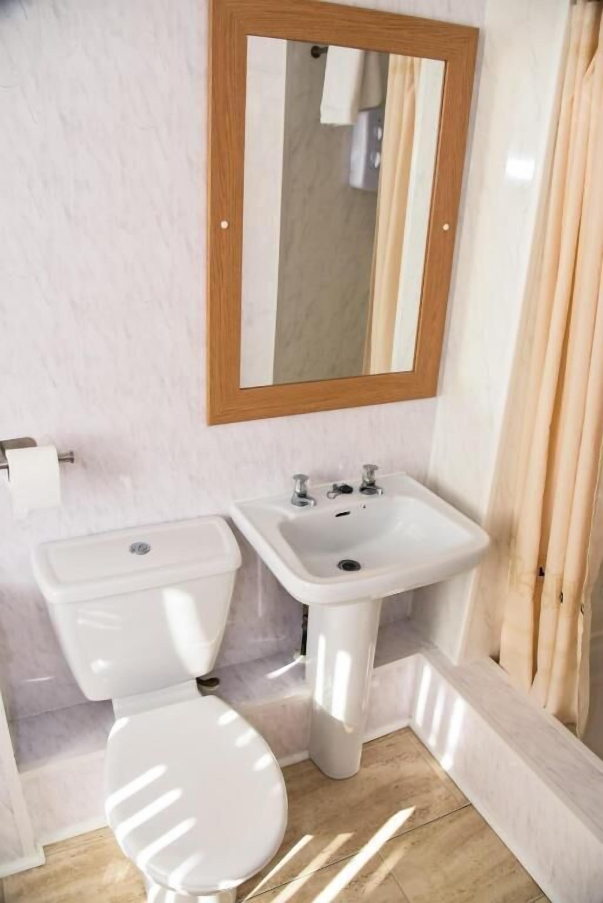 Un baño con inodoro, lavabo y espejo.
