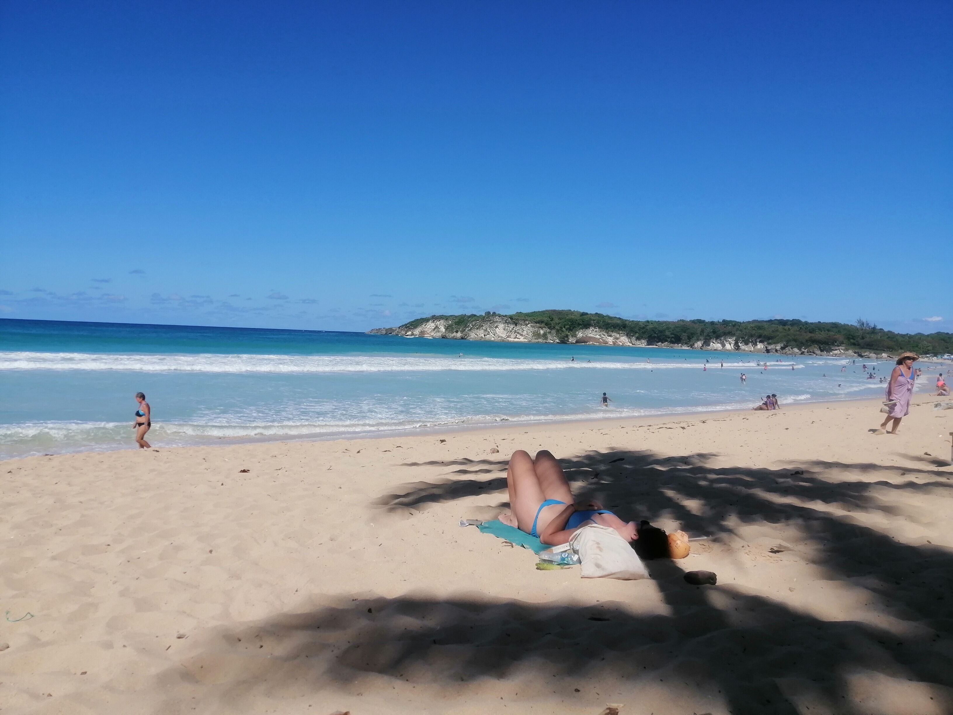 Una spiaggia con persone che prendono il sole e nuotano.