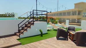 A rooftop terrace with a staircase, lounge chairs, a small table, and a pool in the background. - Macao sky pool suites (Punta Cana)