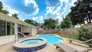 A backyard with a swimming pool, lounge chairs, and a wooden fence. - Family Pool Retreat in Spring , Houston  4BR Private Pool  Sleeps 8 (Spring)