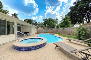 Ein Garten mit Swimmingpool, Liegestühlen und Holzzaun.