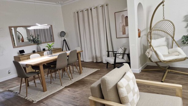 A modern living room with a wooden dining table, chairs, a hanging chair, and a sofa with cushions. - Family Villa with Jacuzzi, Large Garden & Free Parking (Quinta do Conde)