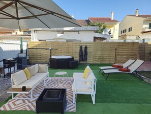 Eine Terrasse mit Gartenmöbeln, einer Feuerstelle und einem Holzzaun.