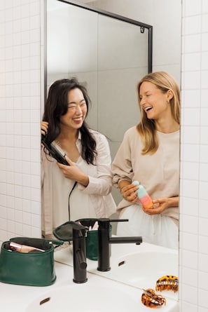 Ein Badezimmer mit Spiegel, Waschbecken und einer grünen Kosmetiktasche auf der Ablagefläche.