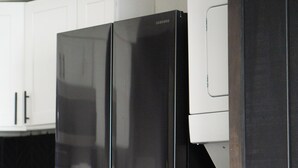 Una cocina con un refrigerador negro, armarios blancos y una encimera de madera.