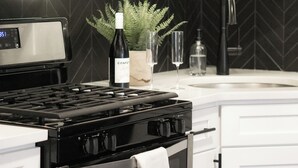 Una cocina moderna con electrodomésticos de acero inoxidable, armarios blancos y un salpicadero negro.