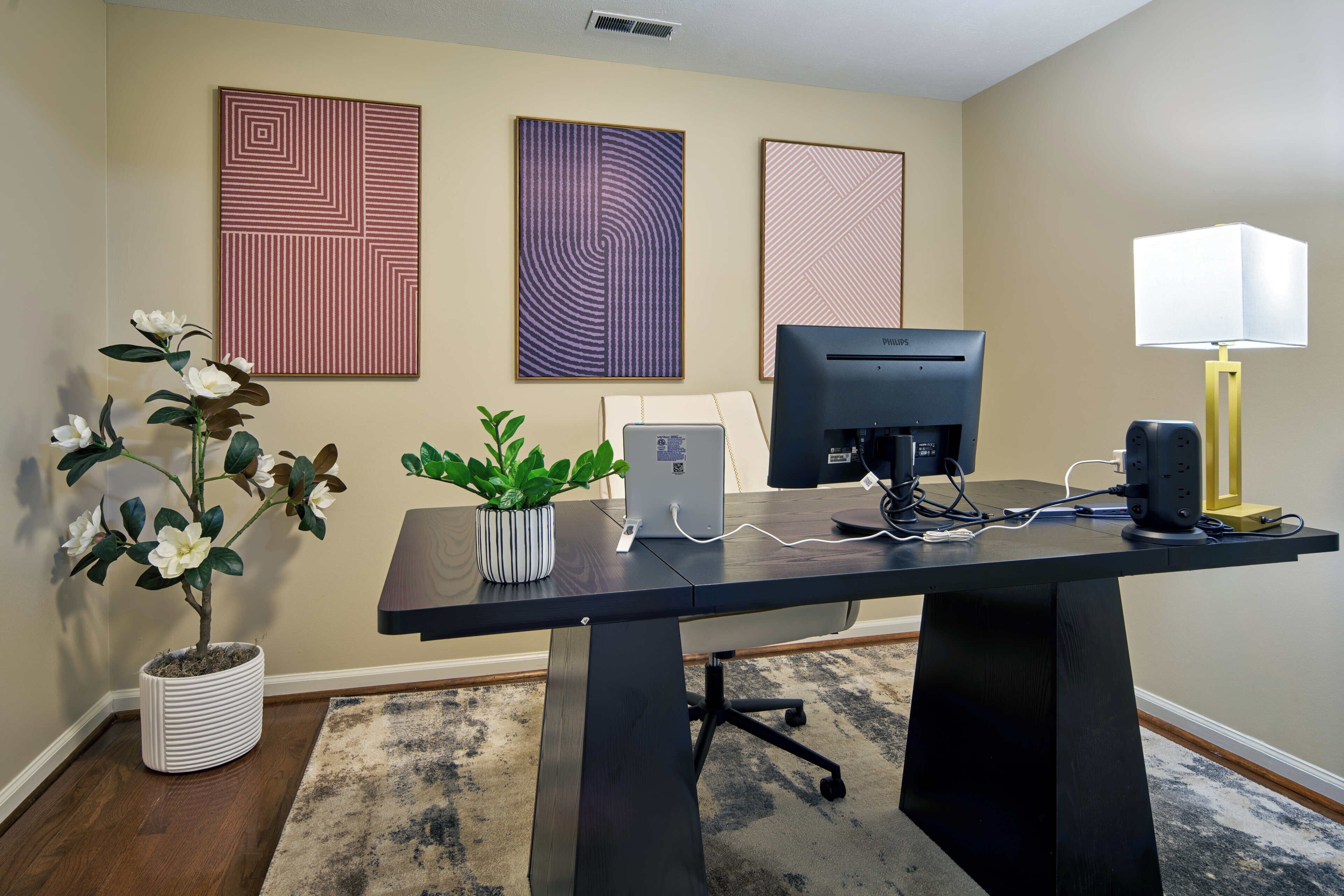 A desk with a computer, a lamp, and a potted plant.