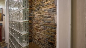A room with a stone wall and a glass block partition.