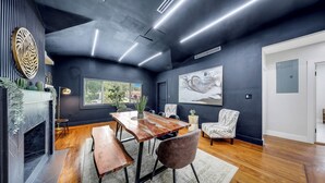 Un intérieur moderne comprenant une table à manger, des chaises, une cheminée et des œuvres d’art accrochées aux murs.