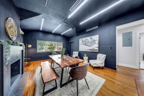 Ein modernes Interieur mit einem Esstisch, Stühlen, einem Kamin und Kunstwerken an den Wänden.