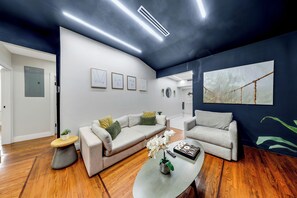 Ein modernes Wohnzimmer mit einem Ecksofa, einem Couchtisch und einem großen abstrakten Gemälde an der Wand.
