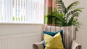 A striped armchair with a cushion, a tray with a plant, and a window with blinds. - Spacious 3BR Hartlepool Stay | Contractor Friendly (Hartlepool)