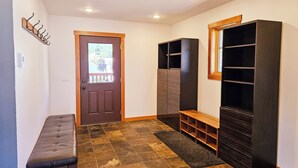 A hallway with a bench, a door with a window, and built-in shelving units.