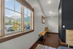 A room with a large window, a bench, a chair, and a wooden cabinet.