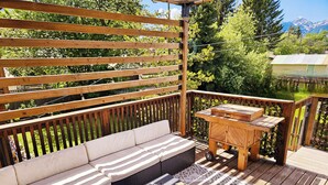 A wooden deck with a sofa, a small table, and a patterned rug.