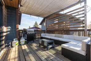 Une terrasse extérieure couverte équipée d’un barbecue, d’un espace salon et de bouteilles de gaz.