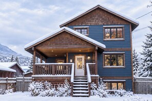 A two-story lodge with a wooden exterior, a front porch, and a staircase leading to the entrance.