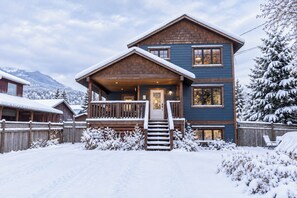 Une maison en bois à deux étages, dotée d’un porche couvert et d’une porte d’entrée.
