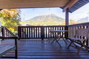 A wooden deck with a table and chairs, overlooking a mountainous landscape. - Fantastic In Town Location (Fernie)