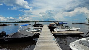 A dock with several boats, a clear sky, and calm water. - Maple Cabin at Pine Ridge Park (Pembroke)