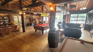 A wooden interior with a pool table, a billiards table, and a bar area with arcade games. - Maple Cabin at Pine Ridge Park (Pembroke)