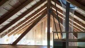 An attic room with wooden beams, a rope ladder, and a view of the outside. - Appartements - N°5 et N°5B by Interhome (Les Genevez)
