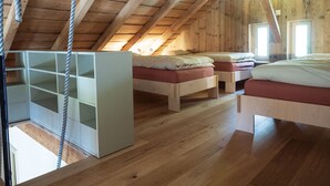A loft-style bedroom with wooden beams, a loft bed, and a white storage unit. - Appartements - N°5 et N°5B by Interhome (Les Genevez)