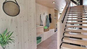 Eine Holztreppe mit Geländer, einer Hängelampe und einer Pflanze in einer Ecke.