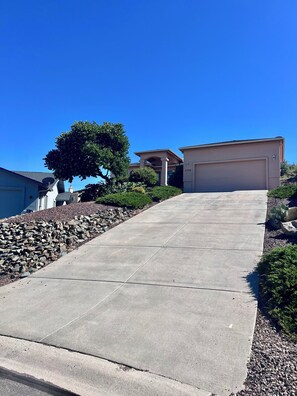 A residential driveway leading to a garage, surrounded by a stone retaining wall and greenery. - Spacious 3Bed/2Ba Prescott Home with Great Views! (Prescott)