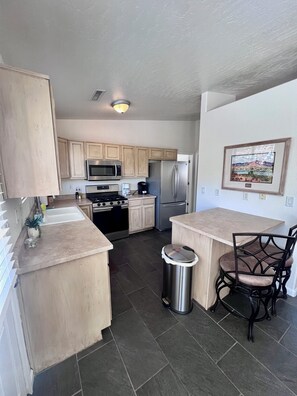 A kitchen with wooden cabinets, stainless steel appliances, a sink, and a trash can. - Spacious 3Bed/2Ba Prescott Home with Great Views! (Prescott)