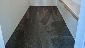 Ein kleiner, leerer begehbarer Kleiderschrank mit einer Deckenleuchte und Holzböden.