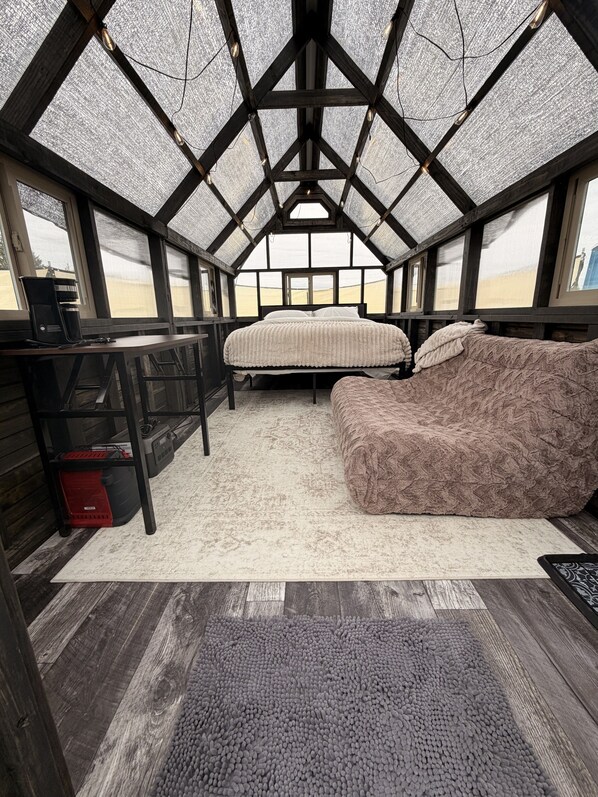 Una habitación con cama, escritorio y un ventanal grande.